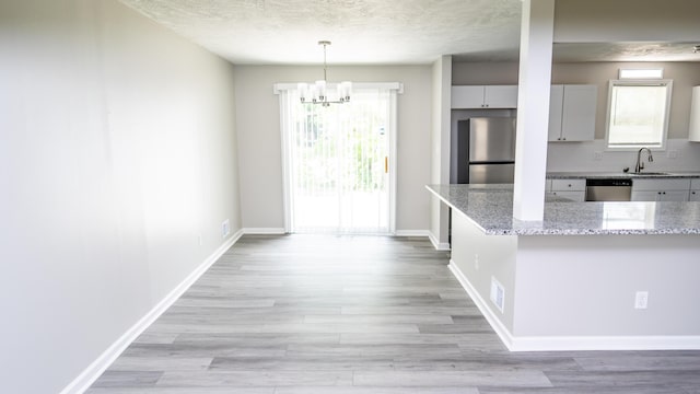 2154 Peppermint Pl, Augusta, GA 30906 - kitchen with light wood finished floors, a sink, stainless steel appliances, a notable chandelier, and light stone counters