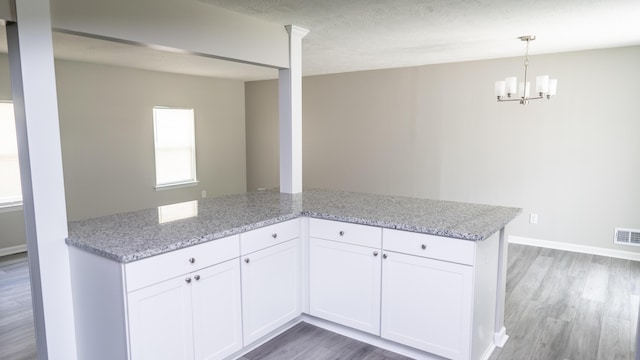 2154 Peppermint Pl, Augusta, GA 30906 - kitchen with light wood-style flooring, light stone counters, a chandelier, and white cabinetry