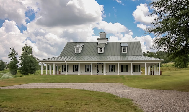 back of house with a standing seam roof, metal roof, a lawn, and gravel driveway