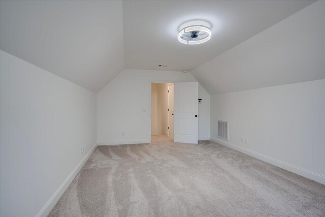 additional living space with light colored carpet and vaulted ceiling