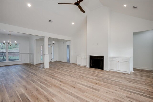 unfurnished living room with ceiling fan with notable chandelier, light hardwood / wood-style floors, and high vaulted ceiling