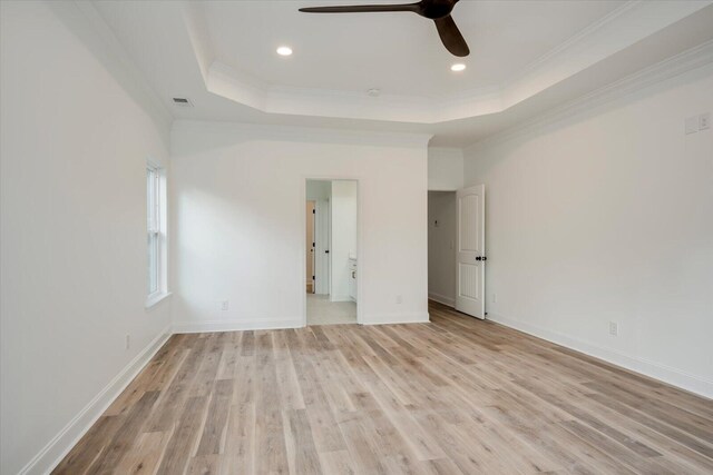 unfurnished room with ceiling fan, a raised ceiling, ornamental molding, and light hardwood / wood-style flooring