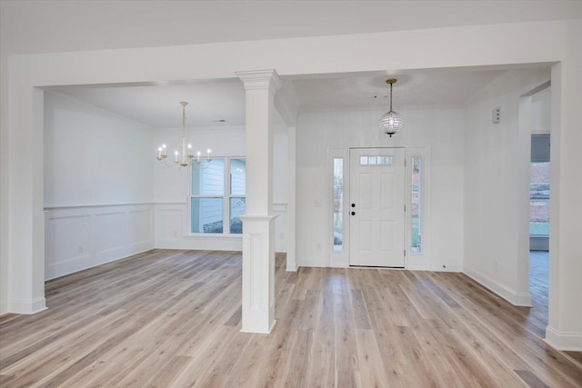 entrance foyer featuring decorative columns, light hardwood / wood-style flooring, a wealth of natural light, and a chandelier