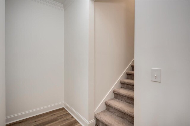 stairs with hardwood / wood-style floors and ornamental molding