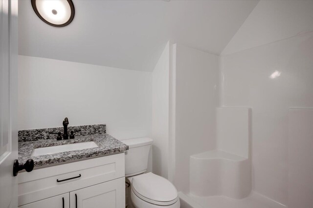 bathroom featuring vanity, toilet, and lofted ceiling