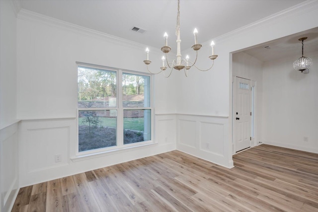 unfurnished dining area with light hardwood / wood-style floors, an inviting chandelier, and ornamental molding