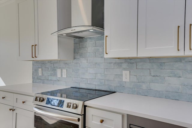 kitchen featuring tasteful backsplash, white cabinetry, stainless steel electric stove, and wall chimney range hood