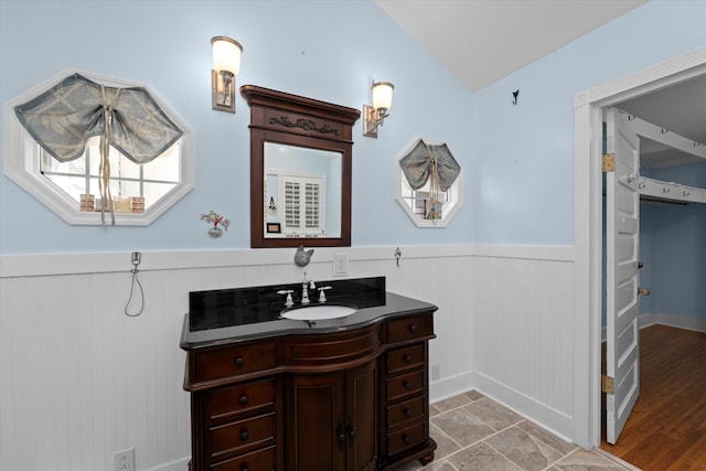 bathroom featuring wood-type flooring, vanity, and vaulted ceiling