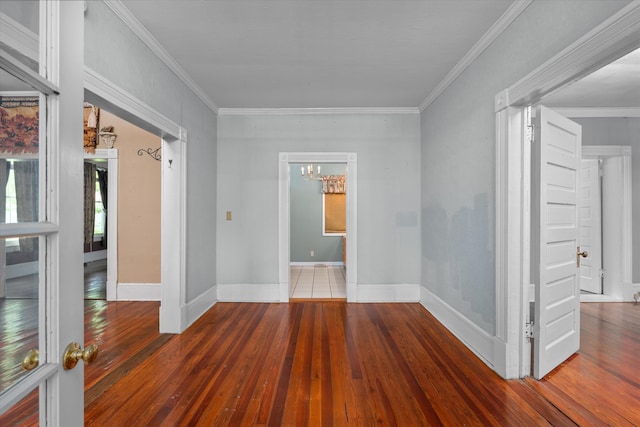 spare room with crown molding, wood-type flooring, and a notable chandelier