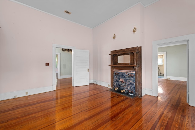 unfurnished living room featuring a high ceiling, dark hardwood / wood-style flooring, and crown molding