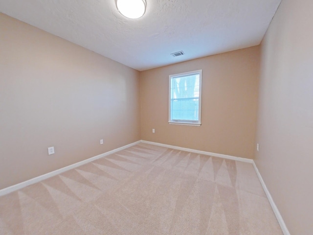 empty room with light carpet and a textured ceiling