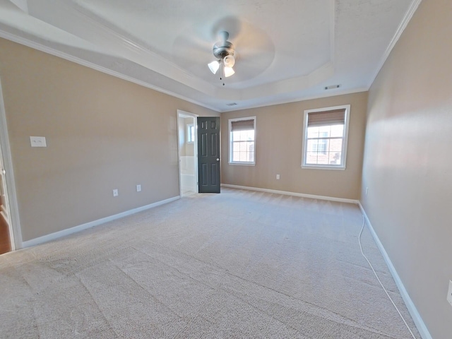 spare room featuring a tray ceiling, ornamental molding, light colored carpet, and ceiling fan