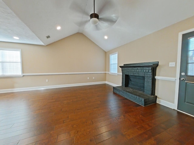 unfurnished living room featuring vaulted ceiling, a wealth of natural light, a fireplace, ceiling fan, and dark wood-type flooring