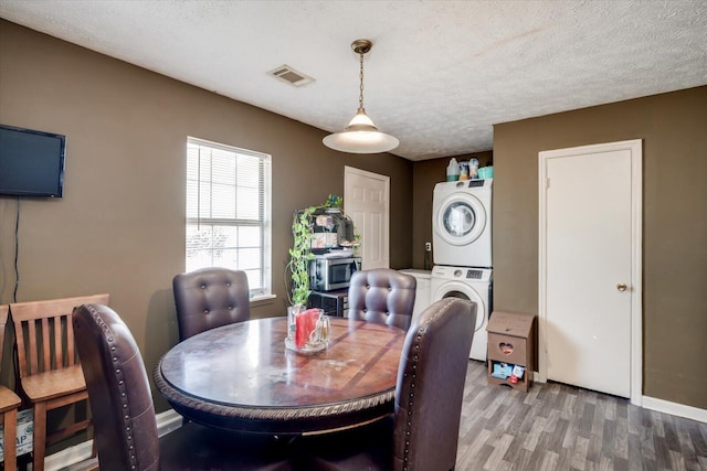 dining room featuring stacked washer and dryer, a textured ceiling, and dark hardwood / wood-style floors