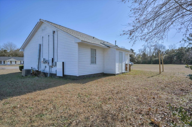 view of side of home featuring central AC unit and a lawn