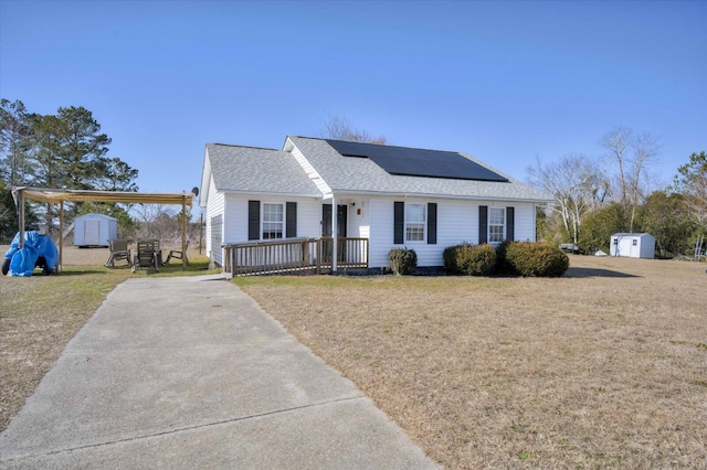 view of front facade with a front yard, a storage shed, and solar panels