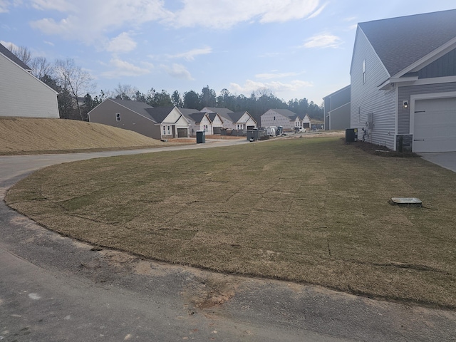 view of yard featuring a garage, a residential view, and central AC