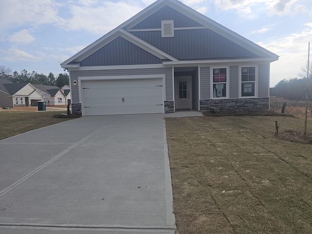 craftsman-style home featuring board and batten siding, concrete driveway, stone siding, and a front yard