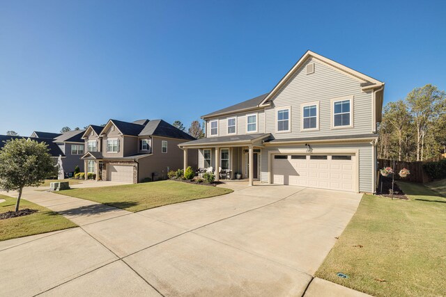 view of front of property featuring covered porch, a garage, and a front yard