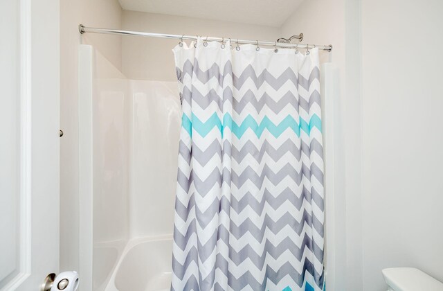 bathroom featuring shower / bathtub combination with curtain and toilet