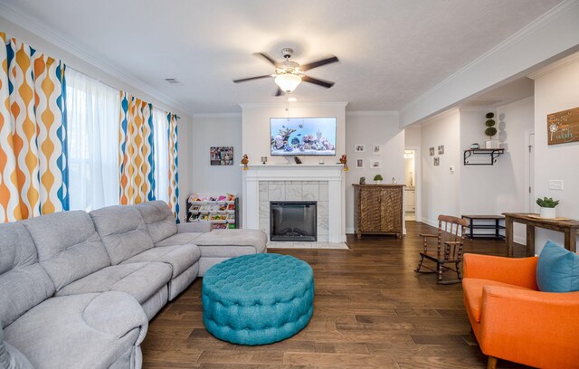 living room featuring a tiled fireplace, ceiling fan, dark wood-type flooring, and ornamental molding