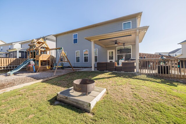 rear view of house with a lawn, ceiling fan, a playground, and an outdoor living space with a fire pit