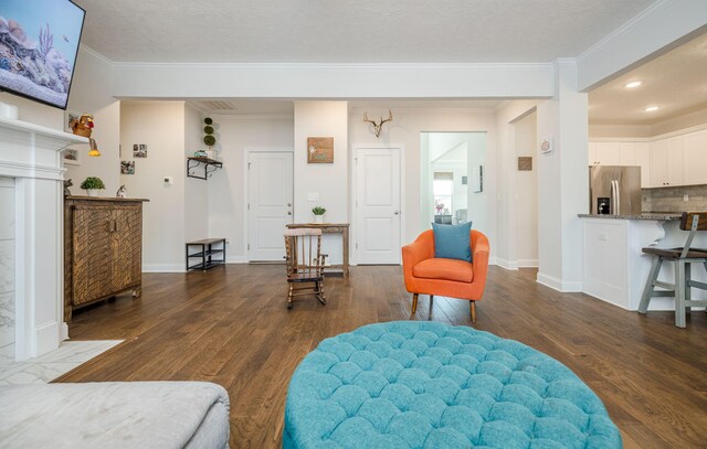 sitting room with dark hardwood / wood-style floors, a fireplace, ornamental molding, and a textured ceiling