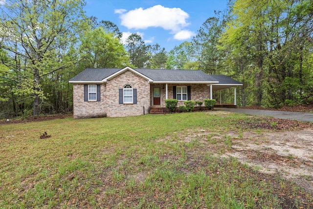 ranch-style home with a carport, brick siding, a front lawn, driveway, and roof with shingles