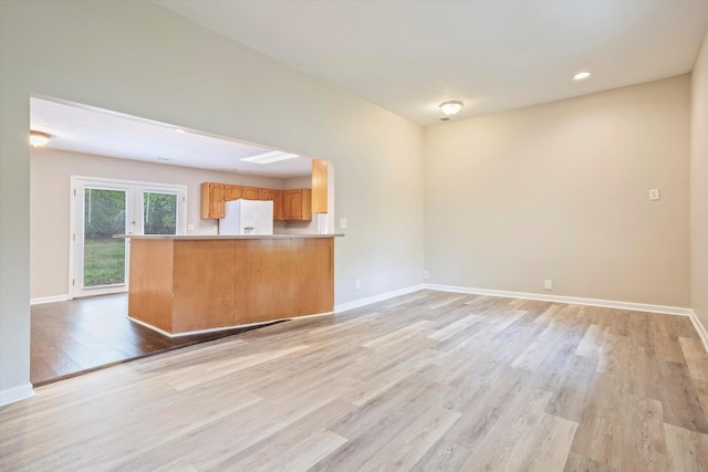 unfurnished living room with recessed lighting, light wood-style flooring, and baseboards