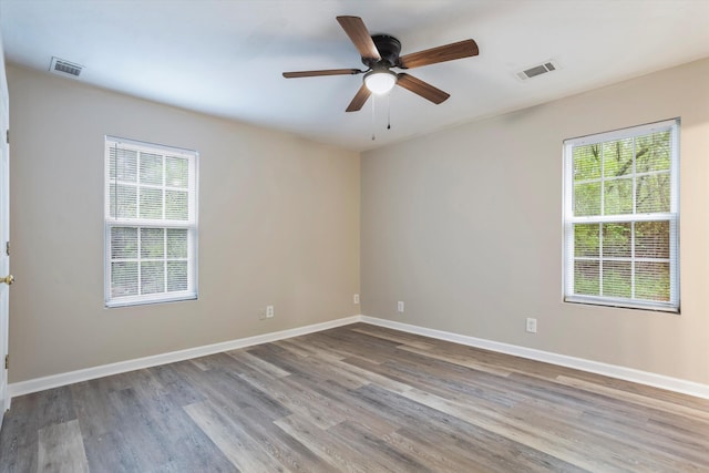 unfurnished room with visible vents, plenty of natural light, and wood finished floors