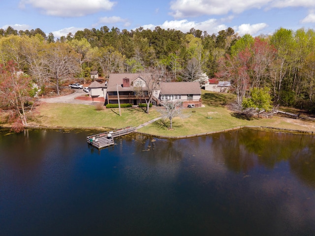 birds eye view of property featuring a water view and a wooded view