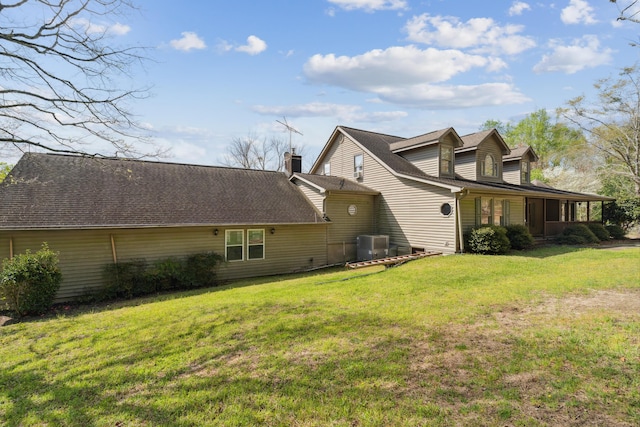 view of side of home featuring a yard, a chimney, and central air condition unit