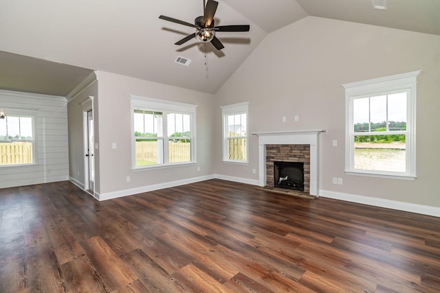 unfurnished living room featuring dark wood-type flooring, a healthy amount of sunlight, visible vents, and a stone fireplace