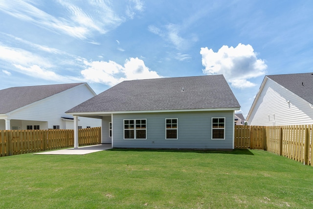 rear view of property with a fenced backyard, a shingled roof, a lawn, and a patio