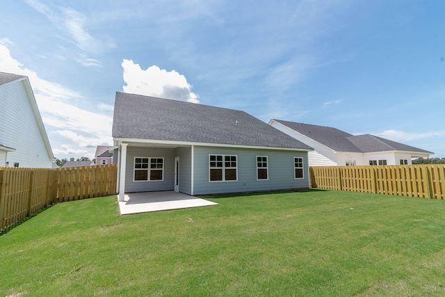 rear view of property featuring roof with shingles, a lawn, a patio area, and a fenced backyard