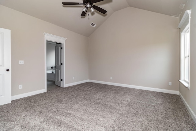 unfurnished bedroom with baseboards, visible vents, ensuite bathroom, vaulted ceiling, and dark carpet