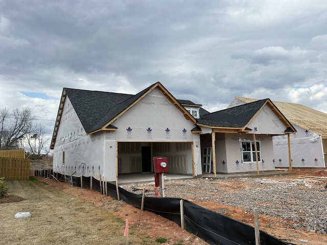 unfinished property featuring an attached garage, fence, and roof with shingles