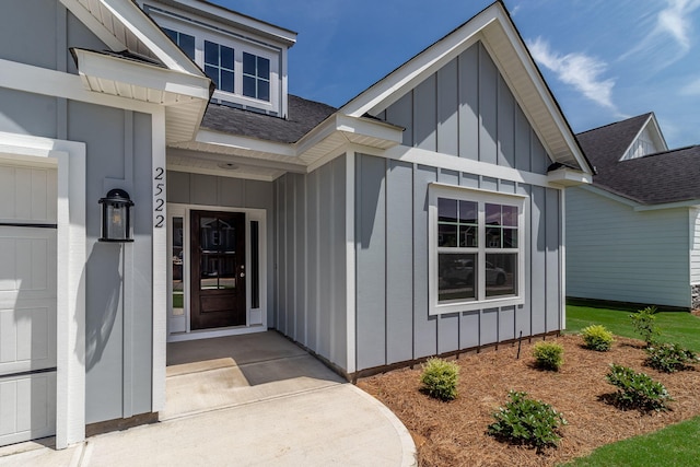 view of exterior entry with a shingled roof and board and batten siding