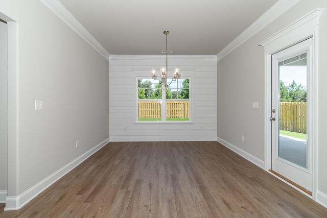 unfurnished dining area featuring ornamental molding, a notable chandelier, plenty of natural light, and wood finished floors