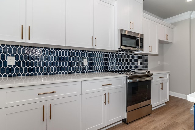 kitchen with crown molding, stainless steel appliances, light countertops, backsplash, and light wood-style flooring