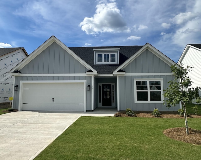 view of front of property featuring roof with shingles, concrete driveway, board and batten siding, a front yard, and a garage