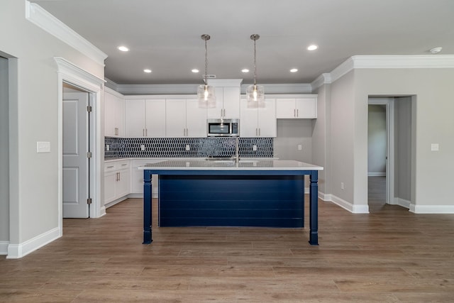 kitchen with stainless steel microwave, backsplash, a kitchen bar, and white cabinetry