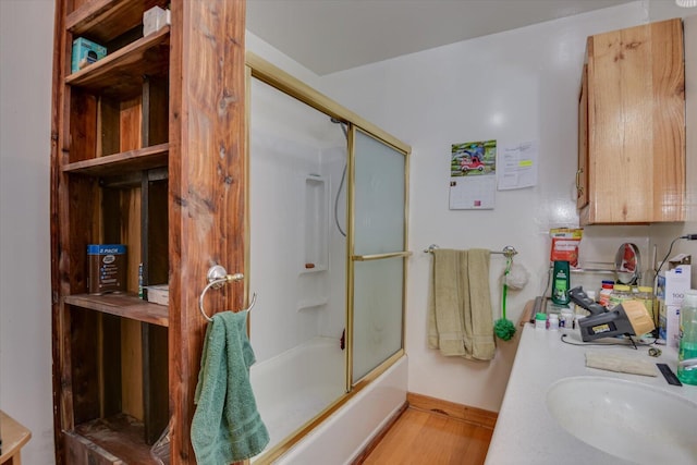 bathroom featuring hardwood / wood-style floors, vanity, and shower / bath combination with glass door