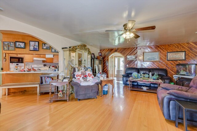 living room featuring wood walls, sink, ceiling fan, and light hardwood / wood-style floors