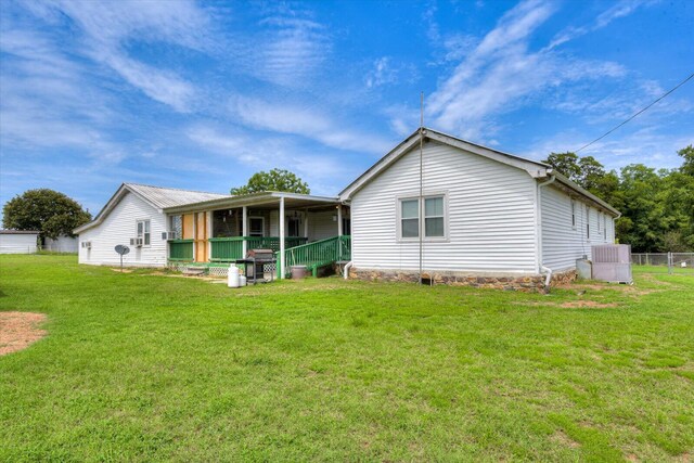 rear view of house featuring a porch, a yard, and central AC