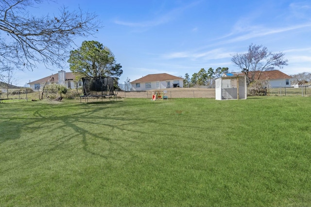 view of yard featuring a trampoline, a playground, and a fenced backyard