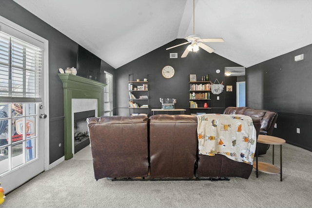 living area featuring lofted ceiling, ceiling fan, a fireplace with flush hearth, visible vents, and carpet