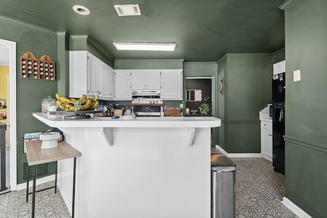 kitchen with a peninsula, a kitchen bar, visible vents, and white cabinets