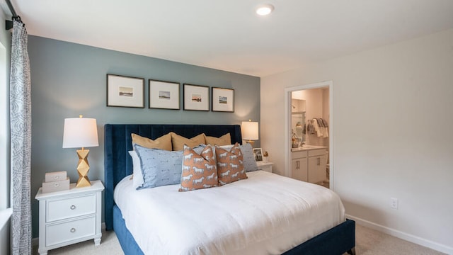 bedroom with ensuite bath and light carpet