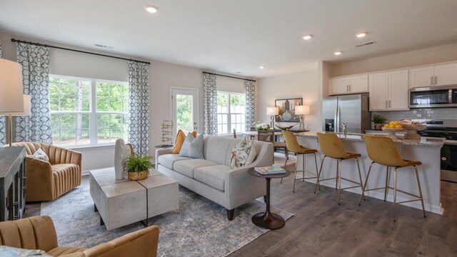 kitchen featuring a center island with sink, appliances with stainless steel finishes, light stone counters, dark hardwood / wood-style flooring, and white cabinets